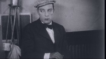 Movie still from “The Dreamers” (2003), directed by Bernardo Bertolucci – A man wearing a hat and a bow tie; Medium shot, High angle