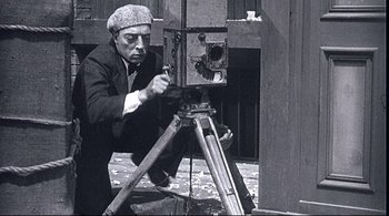 Movie still from “The Dreamers” (2003), directed by Bernardo Bertolucci – An old photo of a man using a camera to take a picture; Medium shot, Low angle