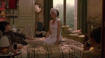 Movie still from “The Dreamers” (2003), directed by Bernardo Bertolucci – A woman sitting on top of a bed next to a window; Medium shot, High angle