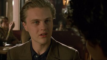 Movie still from “The Dreamers” (2003), directed by Bernardo Bertolucci – A man in a suit and tie looking at the camera; Close Up shot, Over the shoulder angle