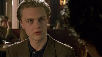 Movie still from “The Dreamers” (2003), directed by Bernardo Bertolucci – A man in a suit and tie looking at the camera; Close Up shot, Over the shoulder angle