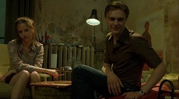 Movie still from “The Dreamers” (2003), directed by Bernardo Bertolucci – A man sitting on the ground in front of a woman; Medium shot, Low angle