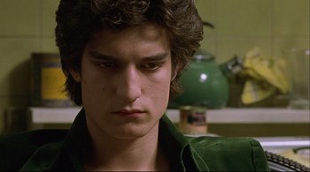 Movie still from “The Dreamers” (2003), directed by Bernardo Bertolucci – A young man in a green shirt is looking at the camera; Close Up shot, Low angle