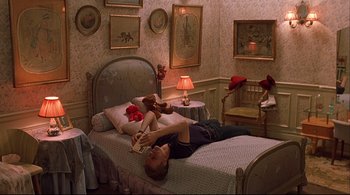 Movie still from “The Dreamers” (2003), directed by Bernardo Bertolucci – A man laying on a bed reading a book; Wide shot, High angle