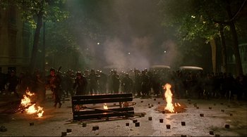Movie still from “The Dreamers” (2003), directed by Bernardo Bertolucci – A group of people standing next to a burning fire; Extreme Wide shot, High angle