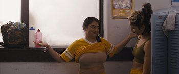 Movie still from “Plan B” (2021), directed by Natalie Morales – A woman in a yellow shirt and a brown skirt; Medium shot, Low angle