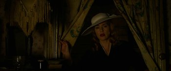 Movie still from “The Dressmaker” (2015), directed by Jocelyn Moorhouse – A woman in a white hat is standing by a window; Medium shot, Low angle
