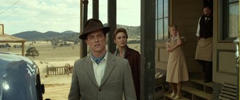 Movie still from “The Dressmaker” (2015), directed by Jocelyn Moorhouse – A man and a woman standing in front of a building; Medium shot, Over the shoulder angle