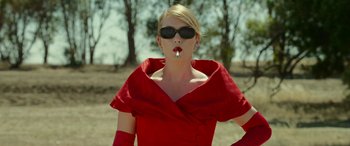 Movie still from “The Dressmaker” (2015), directed by Jocelyn Moorhouse – A woman in a red dress smoking a cigarette in her mouth; Medium shot, Low angle
