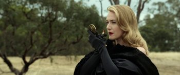 Movie still from “The Dressmaker” (2015), directed by Jocelyn Moorhouse – A woman in a black outfit holding a mirror and lipstick; Close Up shot, Over the shoulder angle