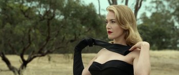 Movie still from “The Dressmaker” (2015), directed by Jocelyn Moorhouse – A beautiful blonde woman wearing a black dress and black gloves; Close Up shot, Low angle