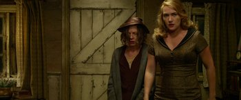 Movie still from “The Dressmaker” (2015), directed by Jocelyn Moorhouse – Two women standing next to each other in front of a wooden door; Medium shot, Low angle