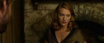 Movie still from “The Dressmaker” (2015), directed by Jocelyn Moorhouse – A beautiful woman with red hair standing next to a brick wall; Close Up shot, High angle