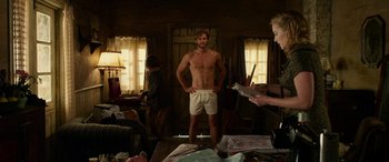 Movie still from “The Dressmaker” (2015), directed by Jocelyn Moorhouse – A shirtless man standing next to a woman in front of a mirror; Medium shot, Over the shoulder angle