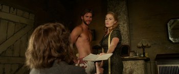 Movie still from “The Dressmaker” (2015), directed by Jocelyn Moorhouse – A man and a woman standing next to each other holding a book; Medium shot, Over the shoulder angle