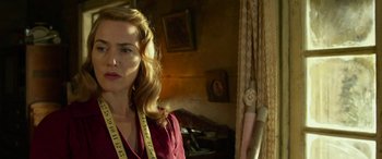 Movie still from “The Dressmaker” (2015), directed by Jocelyn Moorhouse – A woman in a red shirt with a measuring tape around her neck; Medium shot, Low angle