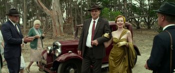 Movie still from “The Dressmaker” (2015), directed by Jocelyn Moorhouse – A man and a woman standing in front of an old car; Medium shot, Low angle