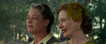Movie still from “The Dressmaker” (2015), directed by Jocelyn Moorhouse – Two women standing next to each other in front of trees; Close Up shot, Over the shoulder angle