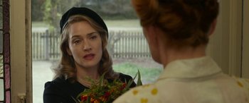 Movie still from “The Dressmaker” (2015), directed by Jocelyn Moorhouse – A woman wearing a hat and holding a bouquet of flowers; Close Up shot, Over the shoulder angle