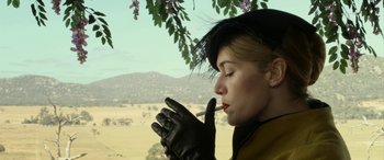 Movie still from “The Dressmaker” (2015), directed by Jocelyn Moorhouse – A woman wearing black gloves and a yellow jacket; Close Up shot, Low angle