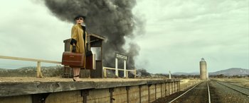 Movie still from “The Dressmaker” (2015), directed by Jocelyn Moorhouse – A woman standing on a train platform near a fire; Wide shot, Low angle