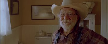 Movie still from “The Dukes of Hazzard” (2005), directed by Jay Chandrasekhar – An older man wearing a cowboy hat in front of a picture; Close Up shot, Low angle
