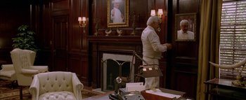 Movie still from “The Dukes of Hazzard” (2005), directed by Jay Chandrasekhar – A man in a white suit is standing in front of a fire place; Wide shot, Low angle