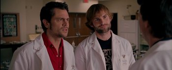 Movie still from “The Dukes of Hazzard” (2005), directed by Jay Chandrasekhar – A couple of men standing next to each other in lab coats; Medium shot, Over the shoulder angle