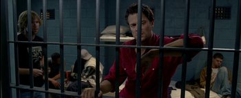 Movie still from “The Dukes of Hazzard” (2005), directed by Jay Chandrasekhar – A man standing behind bars in a jail cell; Medium shot, High angle