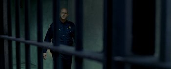 Movie still from “The Dukes of Hazzard” (2005), directed by Jay Chandrasekhar – A police officer standing behind bars in a jail cell; Medium shot, Low angle
