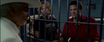 Movie still from “The Dukes of Hazzard” (2005), directed by Jay Chandrasekhar – A group of men sitting next to each other in front of a jail cell; Medium shot, Over the shoulder angle