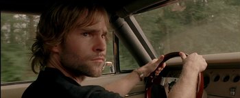 Movie still from “The Dukes of Hazzard” (2005), directed by Jay Chandrasekhar – A man sitting in the drivers seat of a car while holding a steering wheel; Close Up shot, Over the shoulder angle