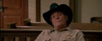 Movie still from “The Dukes of Hazzard” (2005), directed by Jay Chandrasekhar – A man in a sheriff's uniform sitting in a courtroom; Close Up shot, Low angle