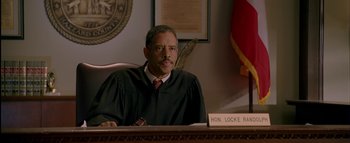 Movie still from “The Dukes of Hazzard” (2005), directed by Jay Chandrasekhar – A judge sitting at a table in a courtroom; Medium shot, High angle