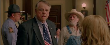 Movie still from “The Dukes of Hazzard” (2005), directed by Jay Chandrasekhar – Two men standing next to each other in front of a door; Medium shot, Over the shoulder angle