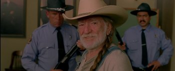 Movie still from “The Dukes of Hazzard” (2005), directed by Jay Chandrasekhar – A man in a cowboy hat with a gun in front of him; Close Up shot, Over the shoulder angle