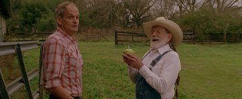 Movie still from “The Dukes of Hazzard” (2005), directed by Jay Chandrasekhar – A man holding an apple next to another man in an open field; Medium shot, Over the shoulder angle