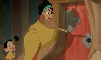Movie still from “The Emperor's New Groove” (2000), directed by Mark Dindal – A woman in a yellow and black dress is pointing to a wall; Medium shot, Over the shoulder angle