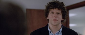 Movie still from “The End of the Tour” (2015), directed by James Ponsoldt – A man with curly brown hair wearing a black jacket; Close Up shot, Over the shoulder angle