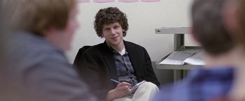 Movie still from “The End of the Tour” (2015), directed by James Ponsoldt – A man sitting in a chair holding a pen and paper; Medium shot, Over the shoulder angle