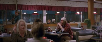 Movie still from “The End of the Tour” (2015), directed by James Ponsoldt – A man sitting at a table in front of two other people; Wide shot, Over the shoulder angle