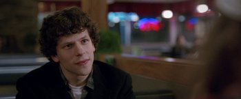 Movie still from “The End of the Tour” (2015), directed by James Ponsoldt – A man sitting at a table in front of a window; Close Up shot, Over the shoulder angle