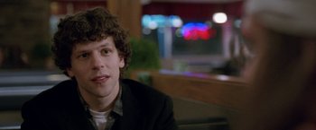 Movie still from “The End of the Tour” (2015), directed by James Ponsoldt – A man sitting at a table in front of a window; Close Up shot, Over the shoulder angle