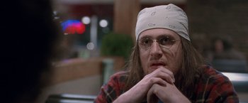 Movie still from “The End of the Tour” (2015), directed by James Ponsoldt – A man with a bandage on his head is sitting in a chair; Close Up shot, Over the shoulder angle