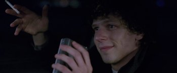 Movie still from “The End of the Tour” (2015), directed by James Ponsoldt – A man holding a cell phone up to his ear; Close Up shot, Over the shoulder angle
