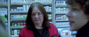 Movie still from “The End of the Tour” (2015), directed by James Ponsoldt – A woman wearing a red jacket standing in a store; Close Up shot, Low angle