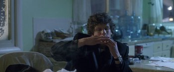 Movie still from “The End of the Tour” (2015), directed by James Ponsoldt – A man with curly hair is smoking a cigarette; Medium shot, Over the shoulder angle