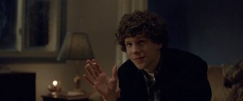 Movie still from “The End of the Tour” (2015), directed by James Ponsoldt – A man with curly hair sitting in front of a lamp; Close Up shot, Over the shoulder angle