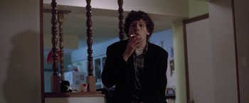 Movie still from “The End of the Tour” (2015), directed by James Ponsoldt – A man sitting in a chair smoking a cigarette; Medium shot, Low angle