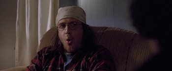 Movie still from “The End of the Tour” (2015), directed by James Ponsoldt – A man sitting on top of a couch wearing a hat; Close Up shot, Low angle